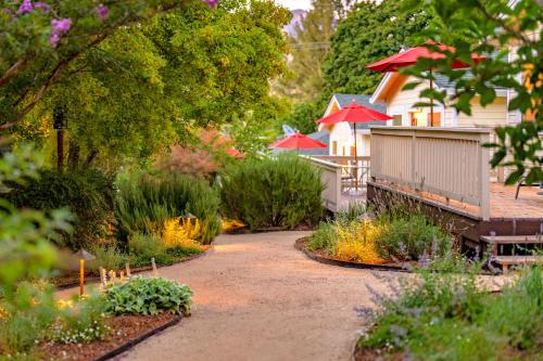 a garden with many plants and red umbrellas at Aurora Park Cottages in Calistoga