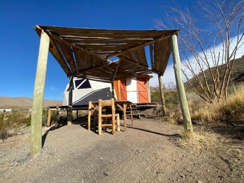 a tent with a table and chairs under it at Domos Andinos HostCamp in Potrerillos