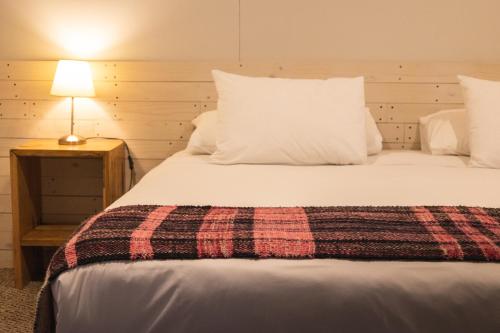 a bedroom with a large bed with a plaid blanket at Hotel Fio Fio in Puerto Williams