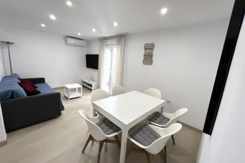 ein Wohnzimmer mit einem weißen Tisch und Stühlen in der Unterkunft Fantástico piso en Benidorm in Benidorm