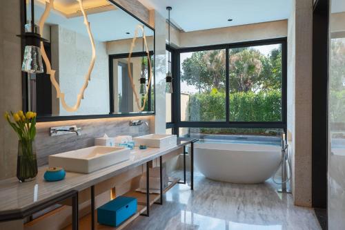 uma casa de banho com 2 lavatórios, uma banheira e uma grande janela. em Renaissance Xiamen Hotel em Xiamen