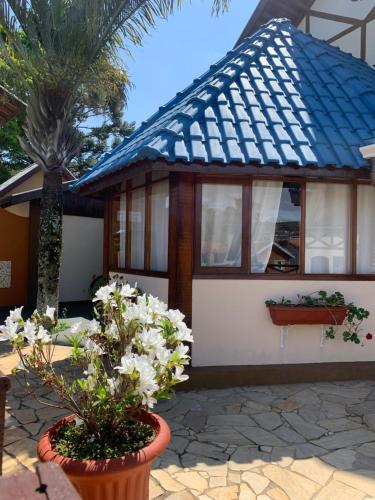 a house with a blue roof and some flowers at Pousada Villa Da Montanha in São Bento do Sapucaí