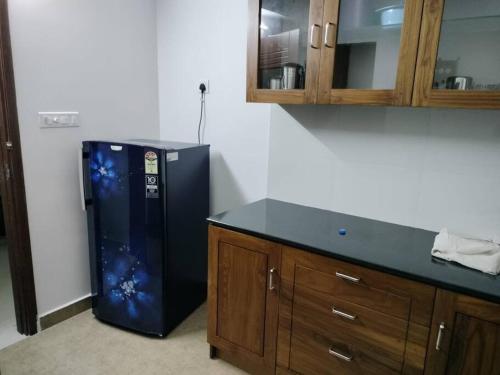 a kitchen with a black refrigerator next to a counter at Ajith's Inn in Kottayam