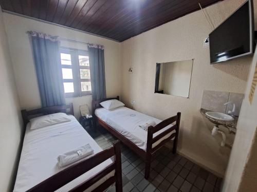 two beds in a room with a sink and a mirror at Pousada Nova Ludovicense in São Luís