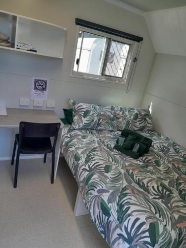 een kamer met een bank en een bureau met een stoel bij AAOK Riverdale Caravan Park in Bundaberg