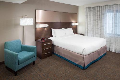 a bedroom with a bed and a blue chair at Residence Inn Kansas City Country Club Plaza in Kansas City