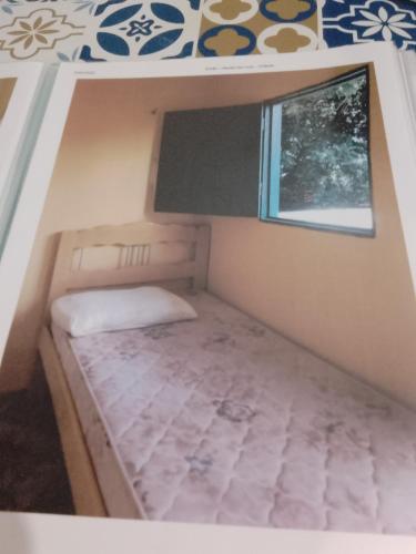 uma pequena cama num pequeno quarto com uma janela em Suítes de Aluguel em Jericoacoara