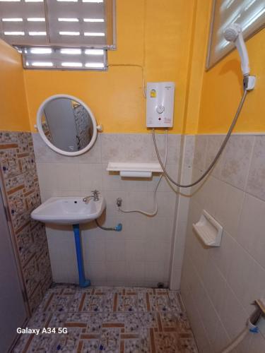 een badkamer met een wastafel en een spiegel bij ริมเมืองโฮมสเตย์ in Phrae