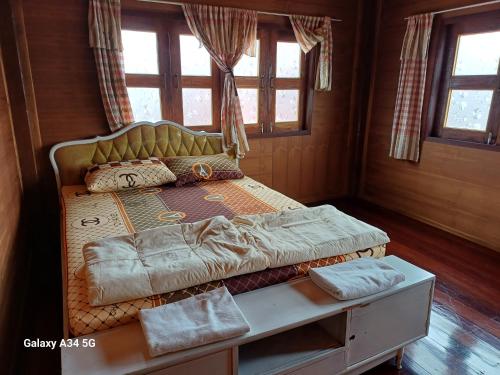 een bed in een kamer met een tafel en ramen bij ริมเมืองโฮมสเตย์ in Phrae