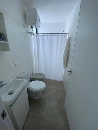 a white bathroom with a toilet and a sink at Apartamento céntrico in Paysandú