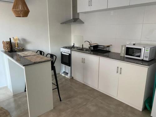 cocina con armarios blancos y microondas en Apartamento céntrico en Paysandú