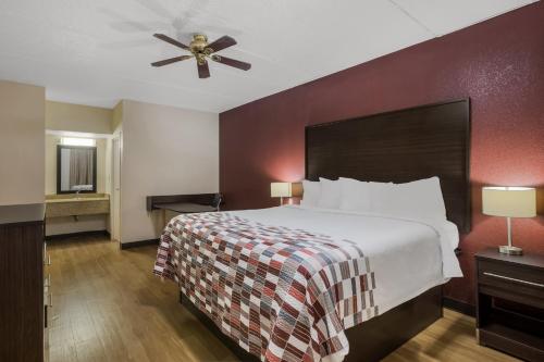 a hotel room with a bed and a ceiling fan at Red Roof Inn & Suites Statesboro - University in Statesboro