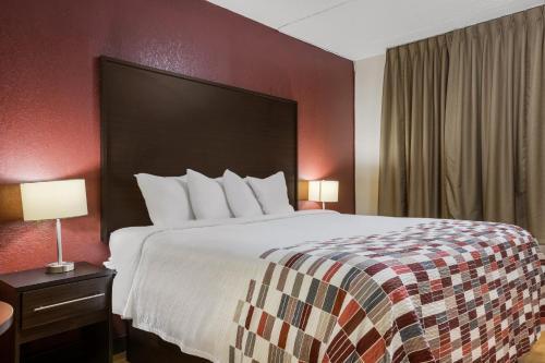 a hotel room with a large bed and red walls at Red Roof Inn & Suites Statesboro - University in Statesboro