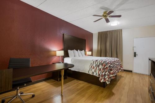 a hotel room with a bed with a desk and a piano at Red Roof Inn & Suites Statesboro - University in Statesboro