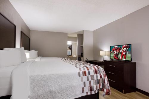 a hotel room with a bed and a flat screen tv at Red Roof Inn & Suites Statesboro - University in Statesboro