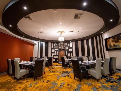 a dining room with tables and chairs and a ceiling at Hotel Araiza Mexicali in Mexicali