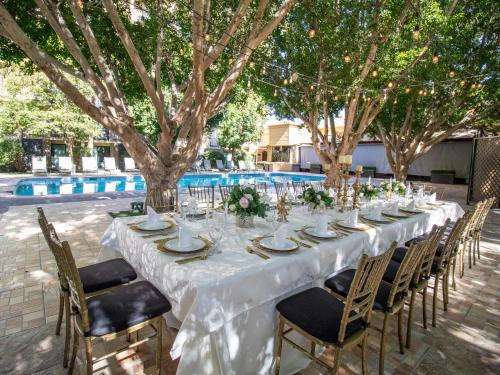 a long table with white tablecloth and chairs and trees at Hotel Araiza Mexicali in Mexicali