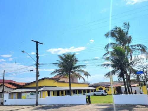 un bâtiment jaune avec des palmiers devant lui dans l'établissement Itamiaru Beach Apartamentos, à Ilha Comprida