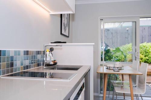 a white kitchen with a sink and a table at Modern Private 2 Bedroom Home-unit in Albany with Netflix in Auckland