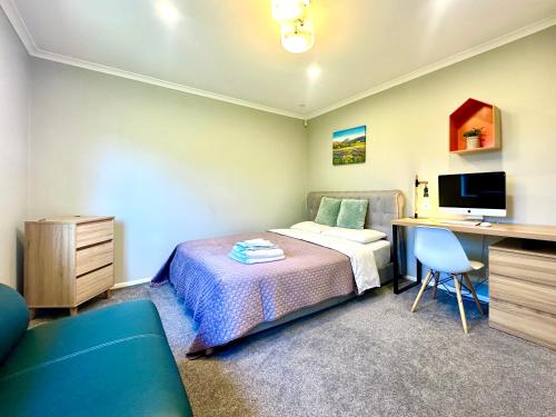 Schlafzimmer mit einem Bett und einem Schreibtisch mit einem Computer in der Unterkunft Modern Private 2 Bedroom Home-unit in Albany with Netflix in Auckland