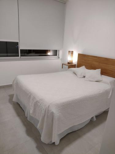 ein weißes Bett in einem weißen Zimmer mit Fenster in der Unterkunft Depto Saladillo in Saladillo