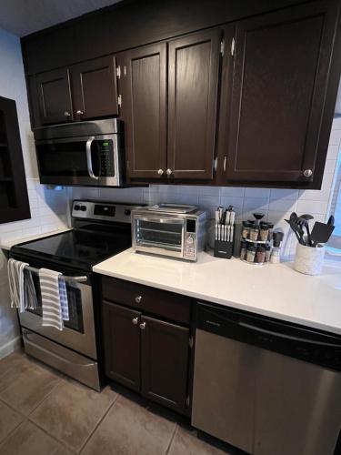 a kitchen with brown cabinets and a stove and a microwave at Beautiful Bungalow in Orlando