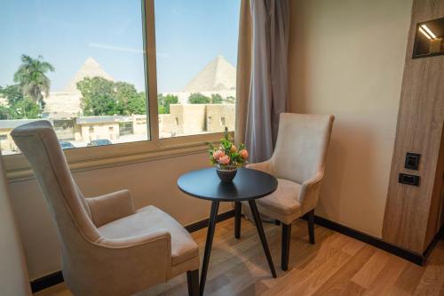 a room with two chairs and a table with a view of the pyramids at Great Pyramid Inn in Cairo