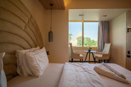 - une chambre avec un grand lit et une table avec des chaises dans l'établissement Great Pyramid Inn, au Caire
