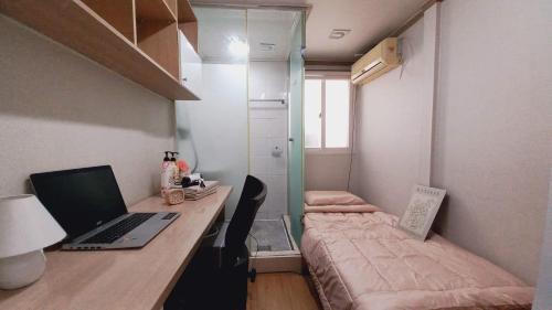 a bedroom with a desk with a laptop and a bed at Haechi Stay GuestHouse - For foreigners only in Seoul