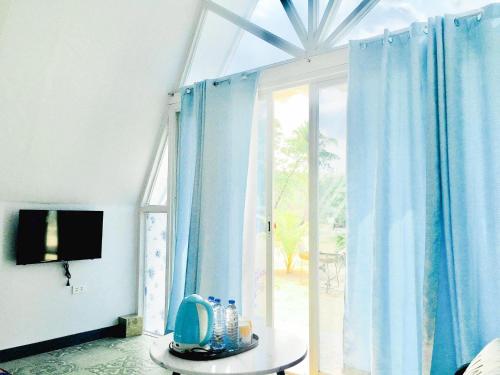 a room with a large window with blue curtains at Bolo Hills Beach Club And Residence in Alaminos