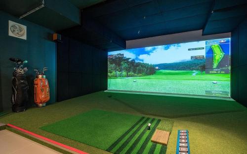 a room with a large screen showing a golf game at Dongnae Hound Hotel Sajik Minam Station in Busan