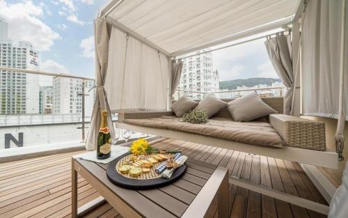 a balcony with a couch and a table with a plate of food at Hound Hotel Minam in Busan