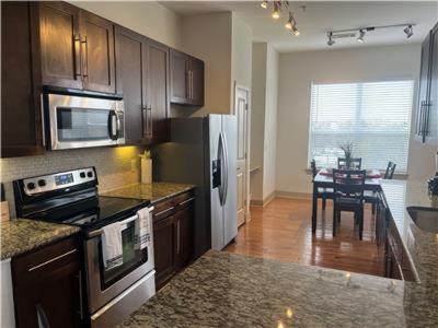 a kitchen with a stove and refrigerator and a table at Gorgeous Furnished Apartments near Texas Medical Center & NRG Stadium in Houston