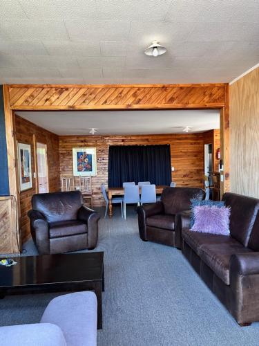 a living room with two leather couches and a table at Alpine Motel in Ohakune