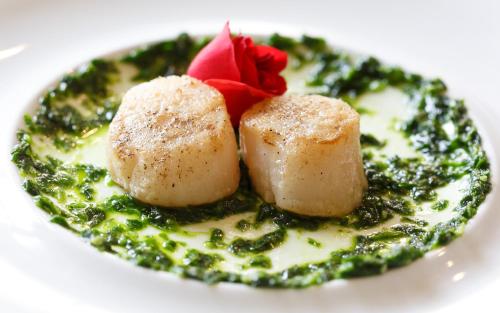a plate of food with dumplings on top of greens at Villa Basileia Riverside in Karlovy Vary