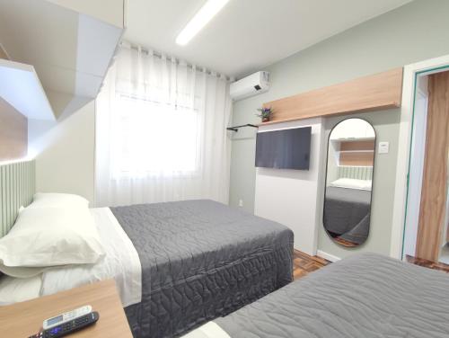 um pequeno quarto com 2 camas e uma televisão em Apartamento Sant'Ana em Porto Alegre