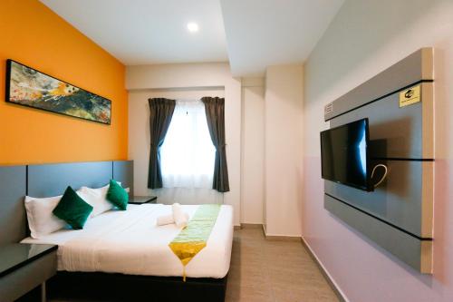 a hotel room with a bed and a tv at Travelland Hotel in Ipoh