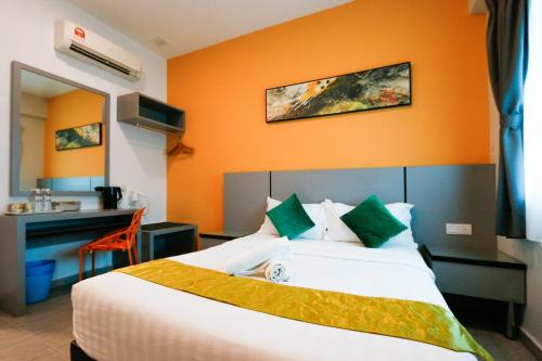 a hotel room with a bed with an orange wall at Travelland Hotel in Ipoh