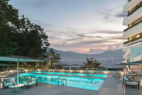 una piscina con sillas y sombrillas en un edificio en TGBS AB 6 Pax, en Medellín