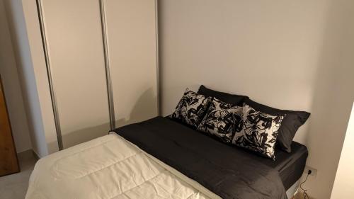 Una cama con una almohada blanca y negra. en Departamento, en centro de Salta Capital. en Salta