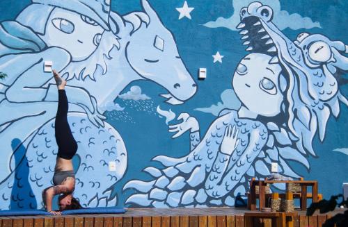 a man doing a pose in front of a mural of horses at Espaço Shanti - Chalés in Sao Jorge