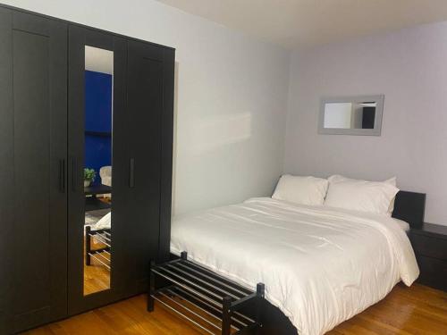 1 dormitorio con 1 cama blanca grande y espejo en Spacious & Cozy Studio, Short Walk to Yale en New Haven