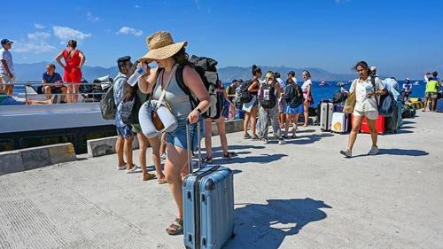 a group of people standing on a pier with luggage at Gilibooking ticket in Padangbai