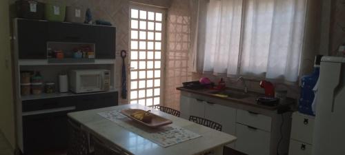 uma cozinha com um lavatório e uma mesa com um micro-ondas em Quarto Divas na Sakura House em Indaiatuba