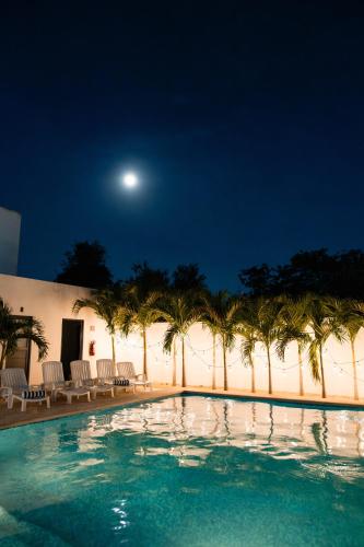 a swimming pool with palm trees and a full moon at Hotel & Suites Yuca Ville Siglo XXI in Mérida