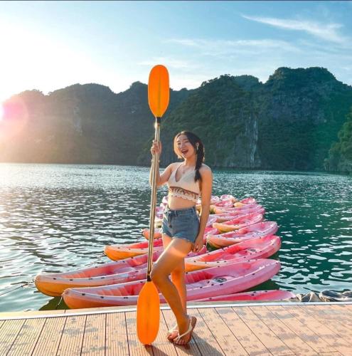 a woman standing on a dock with a row of kayaks at Tung Quang Hotel in Cat Ba