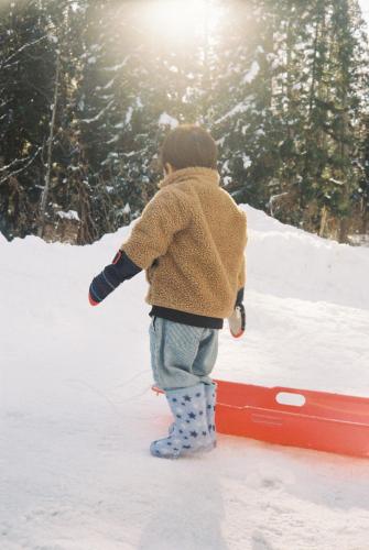 a young child standing on a snowboard in the snow at Pension FOLKLORE in Suginosawa