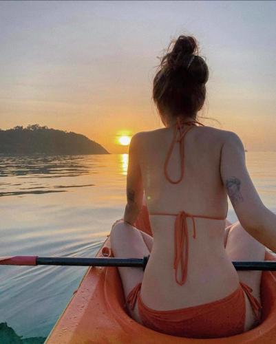 a woman in a kayak on the water watching the sunset at Tung Quang Hotel in Cat Ba
