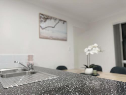 a kitchen counter with a sink and a table at Theme Park Vacation Villa 3 Beds Pimpama in Pimpama