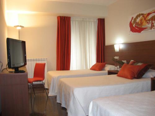 a hotel room with two beds and a flat screen tv at Hotel Txartel in Lasarte